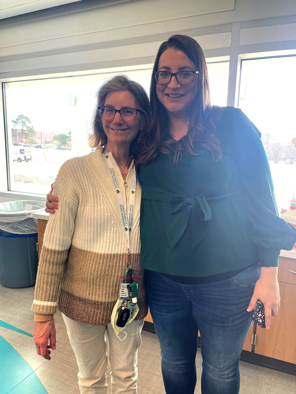 Two smiling faculty members in partial embrace.